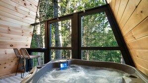 Een hottub in een houten hutje met uitzicht op het bos.