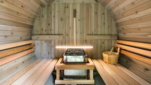 Een sauna met houten banken, een houtgestookte bank en een houten emmer.