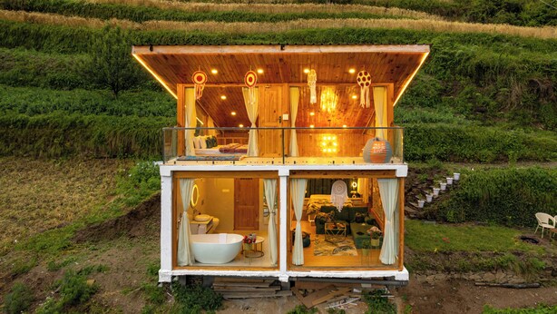 Eine Holzhütte mit Balkon, Bad und Wohnbereich mit Sofa und Tisch.