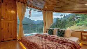 Ein Schlafzimmer mit einem großen Bett, Holzwänden und Blick auf Berge.