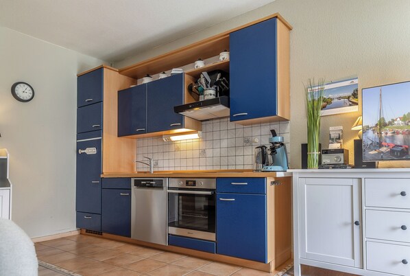A kitchen with blue cabinets, a dishwasher, an oven, and a white countertop.
