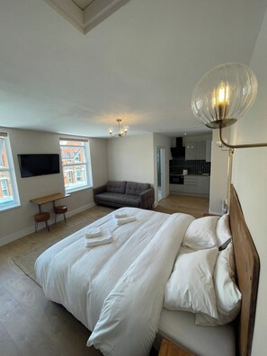 A modern bedroom with a large bed, a sofa, a desk, and a TV. - Central Peckham Studio Retreat (Greater London)