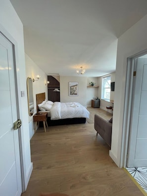 A bedroom with a bed, bedside table, and a wall-mounted mirror.