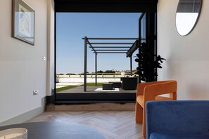A modern living room with a view of a sports field through large glass doors. - The Brighton Skyline 2BR Penthouse (Brighton and Hove)