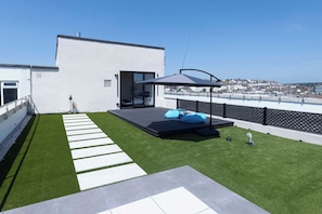 Eine Dachterrasse mit Kunstgrün, eine Sitzgruppe mit blauen Kissen und Blick auf die Skyline.