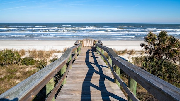 A wooden boardwalk leading to a beach with ocean waves in the background. - Windjammer 115 (St. Augustine)