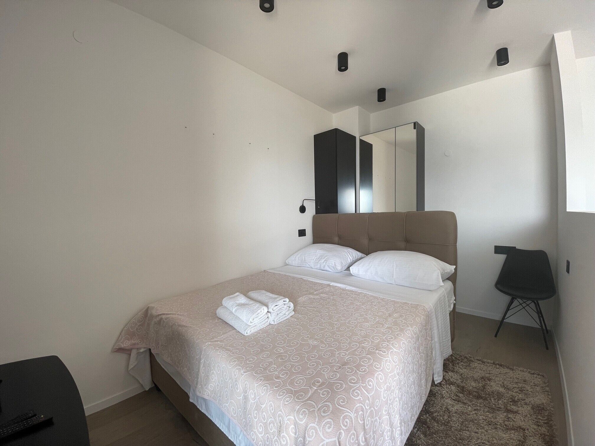 Una camera da letto con un letto, una sedia, una scrivania e uno specchio.
