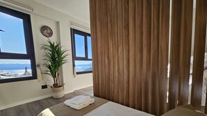 A bedroom with a large bed, two windows with a view, a clock, and a potted plant. - Paradise view Bariloche (San Carlos de Bariloche)