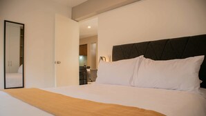 Una habitación de hotel con una cama grande, una manta marrón, un cabecero oscuro y un espejo en la pared.