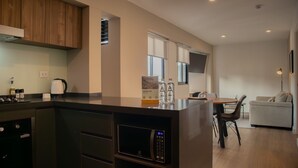 Una cocina moderna con electrodomésticos integrados, un comedor con mesa y sillas, y una sala de estar con sofá.