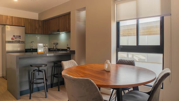 Una cocina moderna con una isla central, taburetes de bar y una mesa de comedor con sillas.