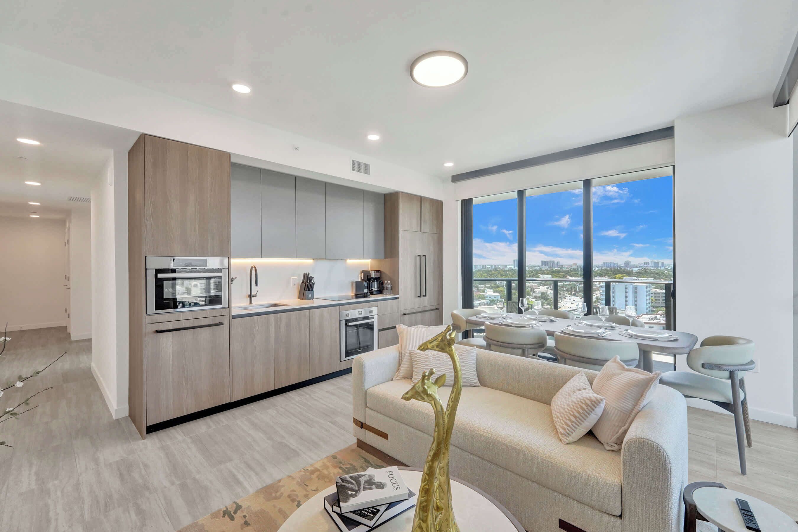 A modern apartment with a kitchen, dining area, and a large window with a city view.