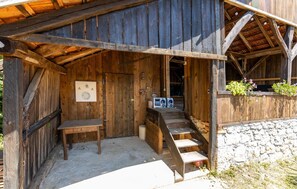 Un bâtiment rustique en bois, doté d’une véranda, de toilettes et d’une petite table.
