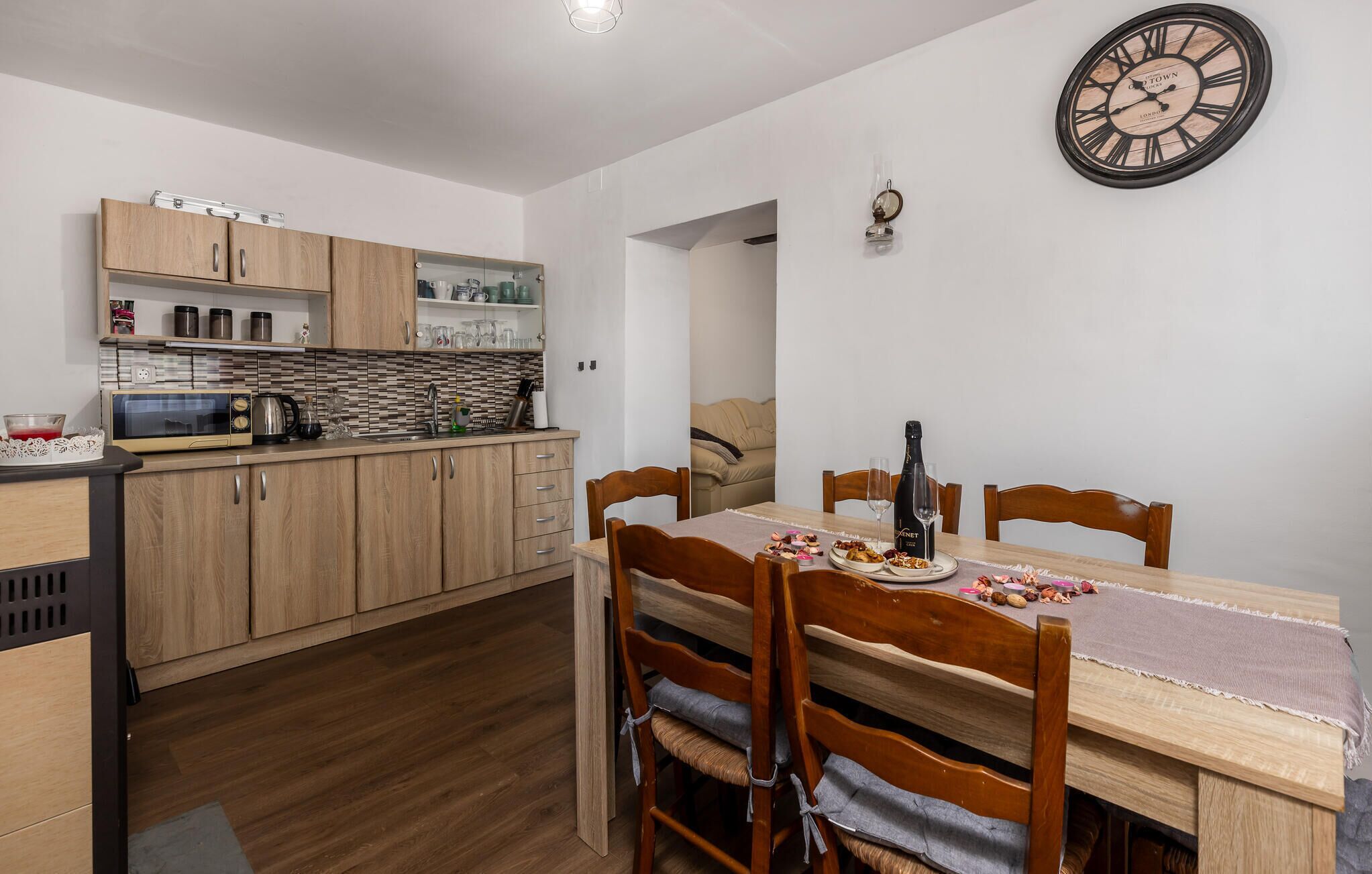 A compact kitchen with wooden cabinets, a microwave, and a dining area with a table set for two.