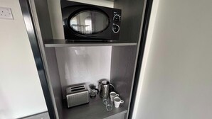 A compact kitchenette with a microwave, toaster, and coffee maker.