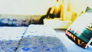 A room with a bed covered in blue patterned bedding, a bedside table with a lamp, and a colorful painting on the wall. - Beautiful apartment in the center of Barcelona (Barcelona)