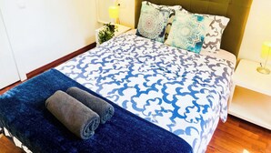 A neatly made bed with patterned bedding, a headboard, and two bedside lamps. - Beautiful apartment in the center of Barcelona (Barcelona)