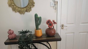 A wooden console table with a mirror, cactus, and decorative vases against a white wall. - Charming Victorian Apartment in Central Wolverhampton (Wolverhampton)