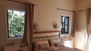 Un dormitorio con una cama, una silla, dos ventanas y un radiador.