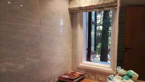 Un baño con ventana, un mueble para revistas y un perchero.