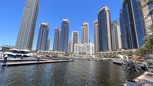 Un port de plaisance où sont amarrés des bateaux, entouré de gratte-ciel et de palmiers.
