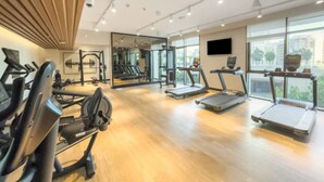 Une salle de sport moderne équipée de machines de cardio, d’appareils de musculation et de grandes fenêtres offrant une vue sur la ville.