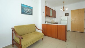 Ein Wohnzimmer mit Sofa, Holzschränken, einer Küchenzeile und einer Tür.