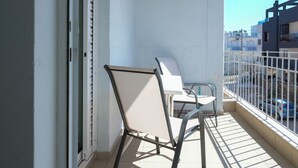 Ein Balkon mit zwei Stühlen, einer weißen Decke und Blick auf Gebäude.