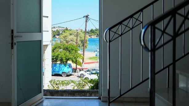 Ein Flur, der zu einem Balkon mit freiem Blick auf ein blaues Auto und Grünanlagen führt.