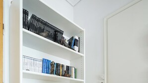 Ein weißes Bücherregal mit blauen unteren Böden, einer roten Vase und verschiedenen Büchern.