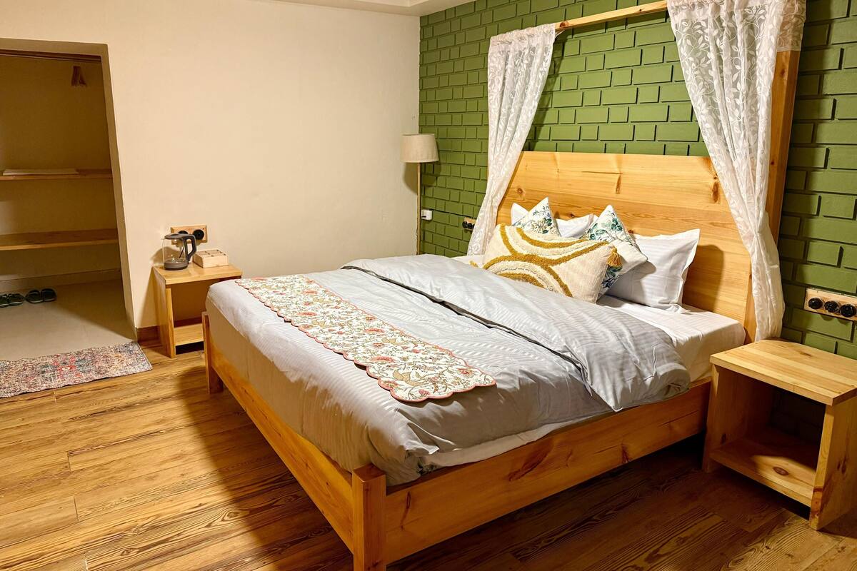 Un lit en bois avec un mur en briques vertes, une table de chevet avec une lampe et une tête de lit en bois.