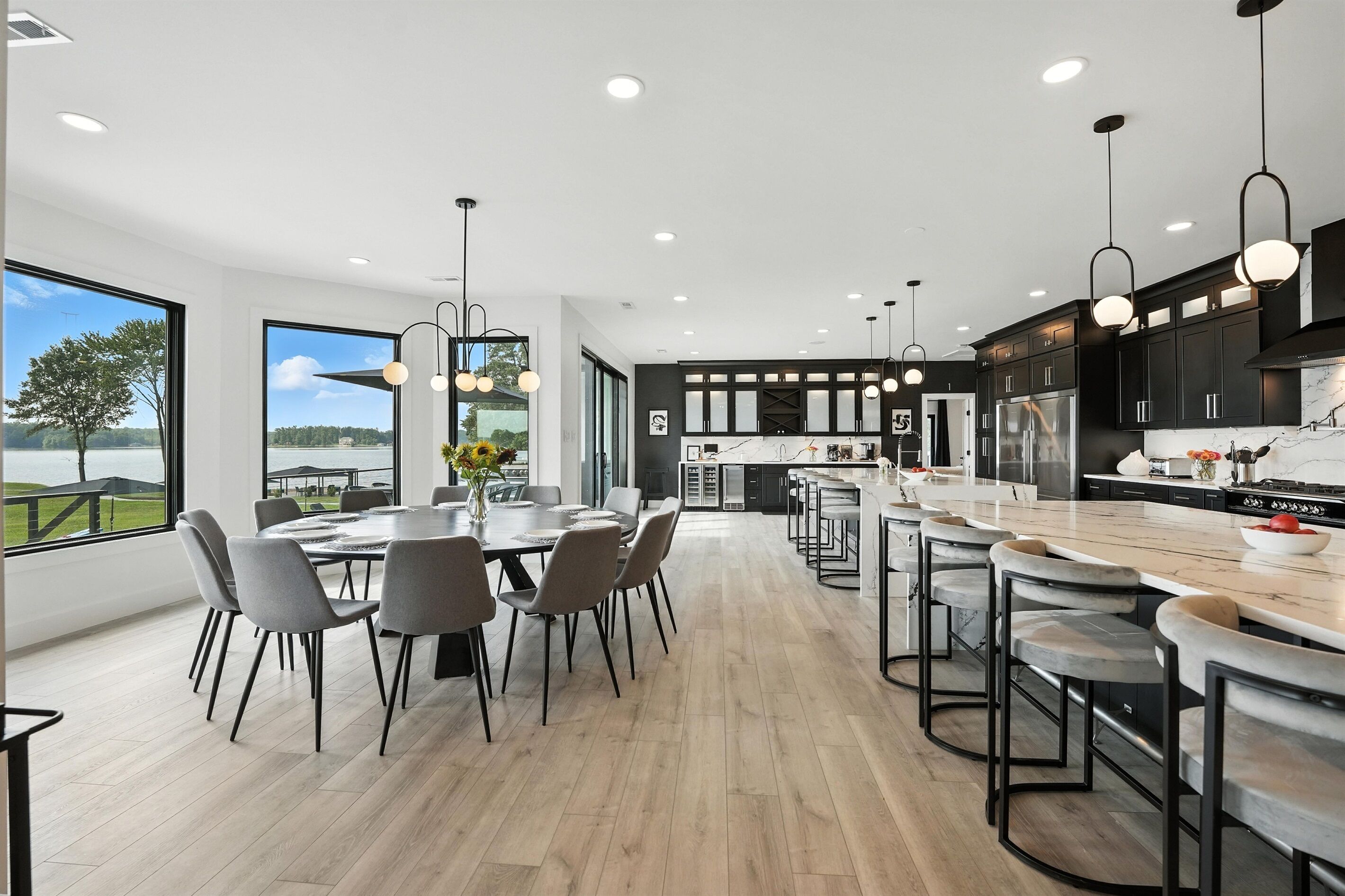 Una cocina moderna con una isla central, asientos tipo bar y ventanas amplias que ofrecen vistas al exterior.