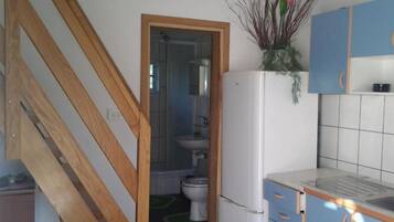Una cocina con un refrigerador blanco, armarios azules y una escalera de madera.