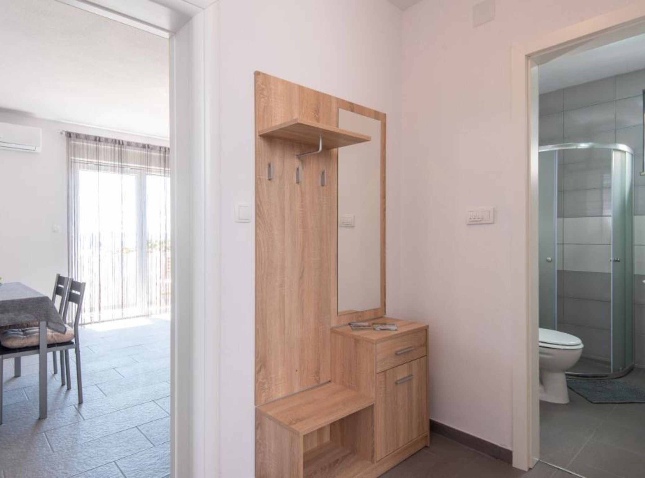 A modern bathroom with a glass shower enclosure, a wooden vanity with a mirror, and a toilet.