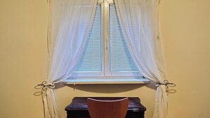 A corner room with a window, a wooden chair, and a small table. - Lily BUDAPEST - Quiet apartment with garden view in the heart of the city center (Budapest)