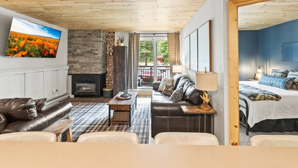 A cozy living room with a fireplace, leather sofas, a TV, and a view of the outdoors. - Ski-In/Out Luxury•1 Blk to Main•Pool+Hot Tub•Sauna (Breckenridge)