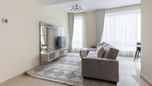 Una sala de estar moderna con un sofá gris, un televisor de pantalla plana y una alfombra estampada.