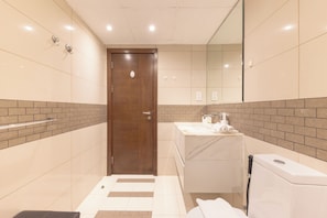 A modern bathroom with a wooden door, a white sink, and a mirror.