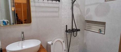 Une salle de bain moderne équipée d’un lavabo, de toilettes et d’une douche.