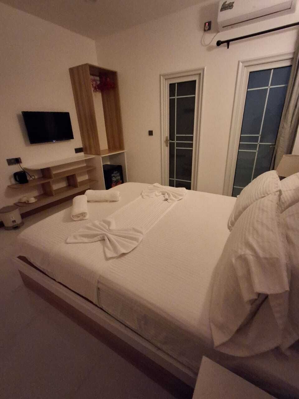 Una habitación de hotel con cama, televisión, armario y ventana.