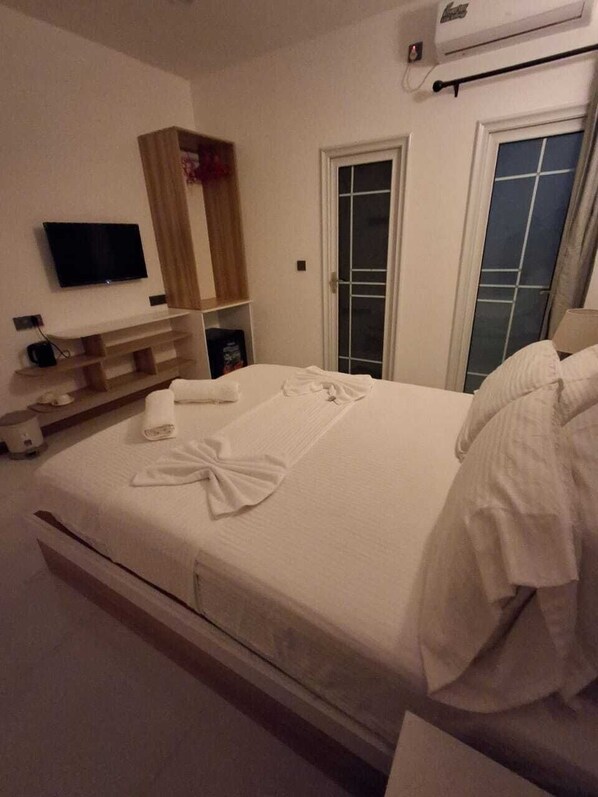 A hotel room with a bed, a TV, a wardrobe, and a window.