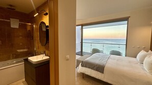 A modern bathroom with a sink and mirror, and a bedroom with a bed and a view of the sea. - Luz by Check-in Portugal (Lagos)