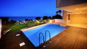 A swimming pool with a view of the ocean, surrounded by a wooden deck and lounge chairs. - Luz by Check-in Portugal (Lagos)