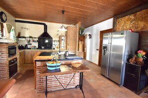 Une cuisine dotée d’un îlot central en briques, d’un réfrigérateur en acier inoxydable et d’un mur décoratif en pierre.