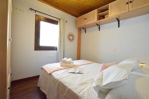 Une chambre à coucher avec un lit, une fenêtre, une étagère fixée au mur et une porte.