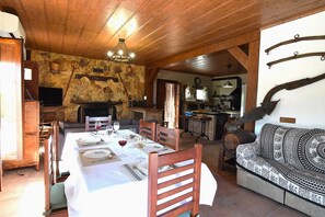 A dining area with a long table set for a meal, wooden chairs, and a stone wall. - Idyllic Andalusian villa with private pool & stunning views (Riogordo)