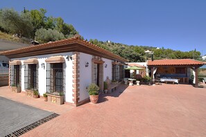 A building with a tiled roof and a patio area with a table and chairs.