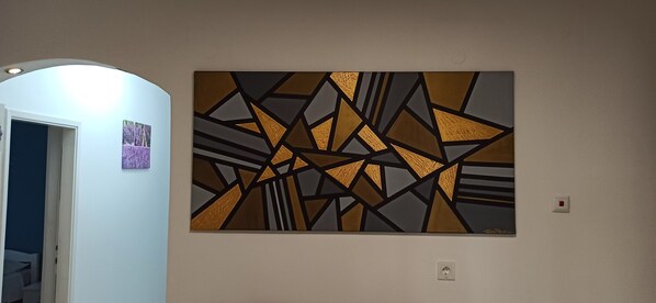 A room with a large abstract painting on the wall, a door leading to another room, and a light switch. - Apartments Desa Petric  (Hvar)