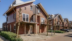 Ein modernes Wohngebäude mit flachem Dach, großen Fenstern und einem Balkon.