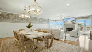 A dining area with a large table, upholstered chairs, and a chandelier. - On Beach 5BD+7BA: Sauna|HotTub|Billards|FencedDeck (Norfolk)